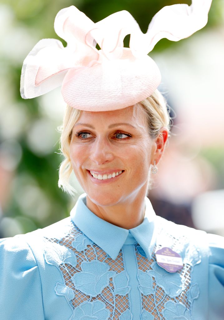  Zara Tindall smiling shoulders up in blue dress and pink hat