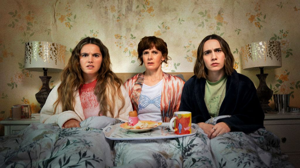 mother and two daughters sitting in bed