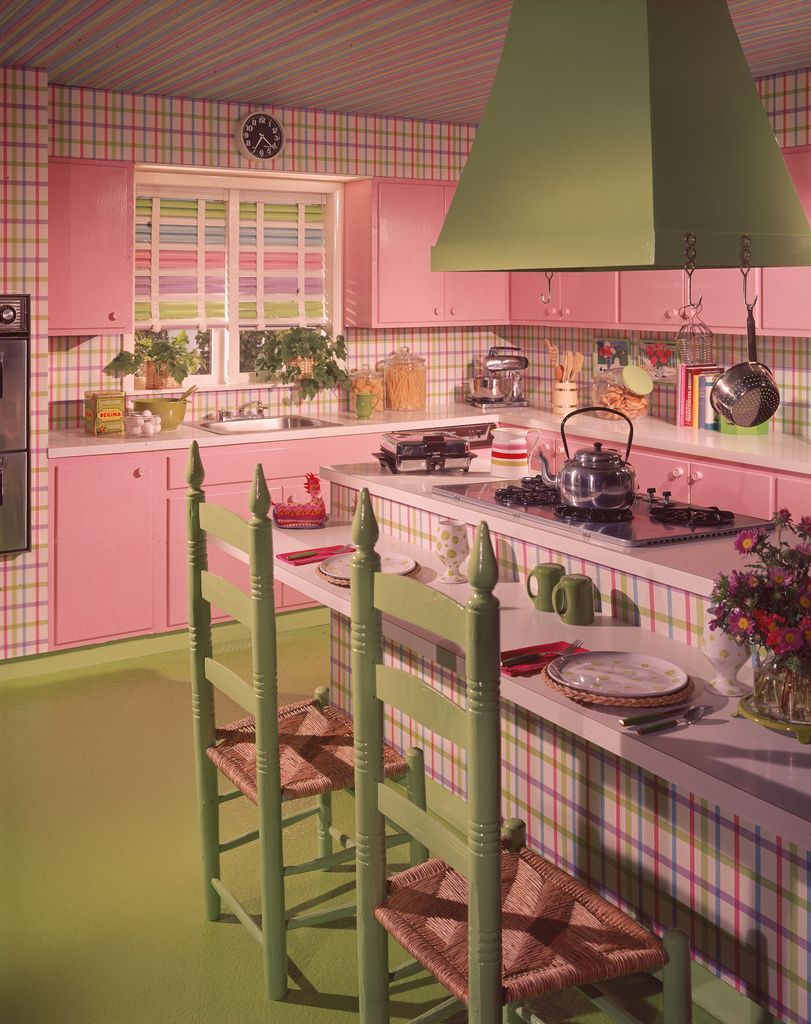Interior view of a pink and lime green kitchen with a center island with stove, counter, and chairs, circa 1980. (Photo by Frederic Lewis/Getty Images)