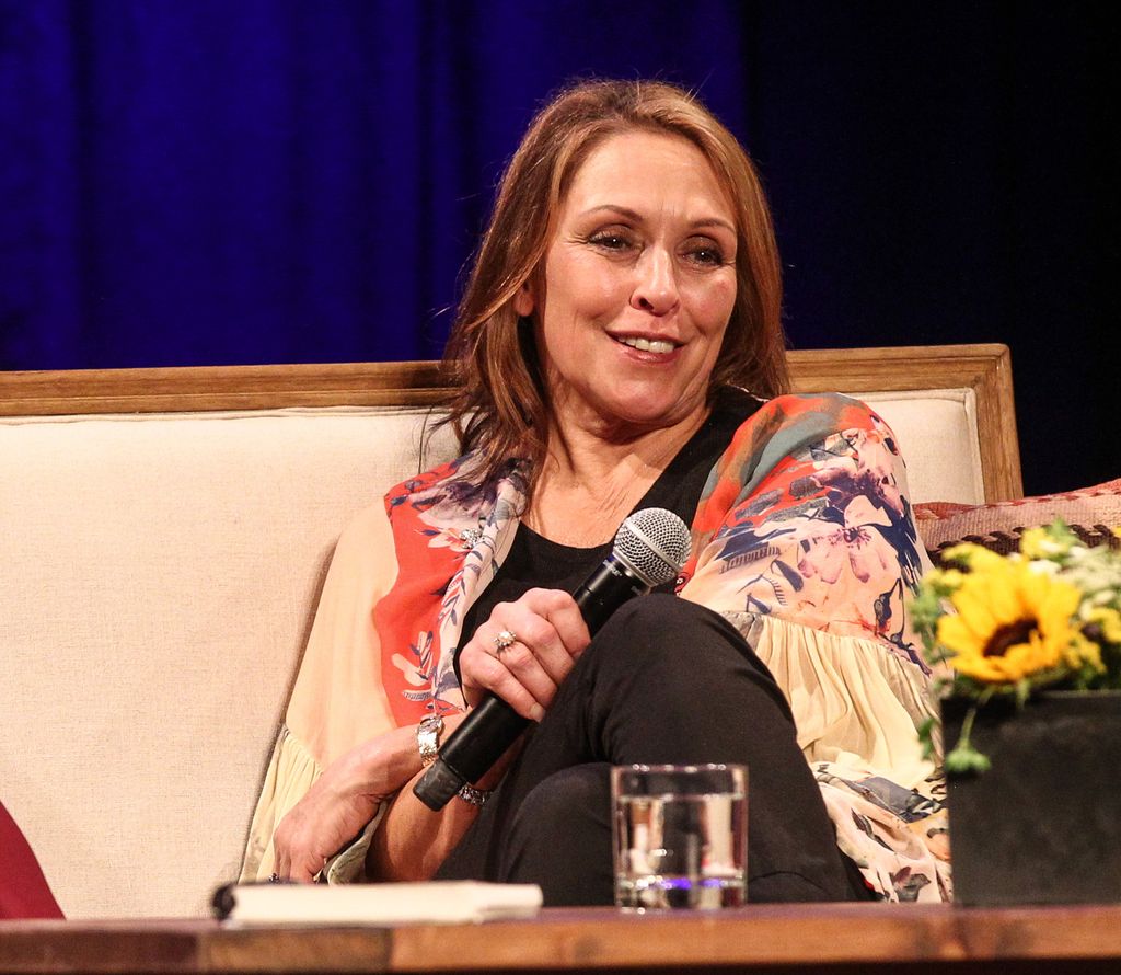 cindy cash holding mic sitting on couch