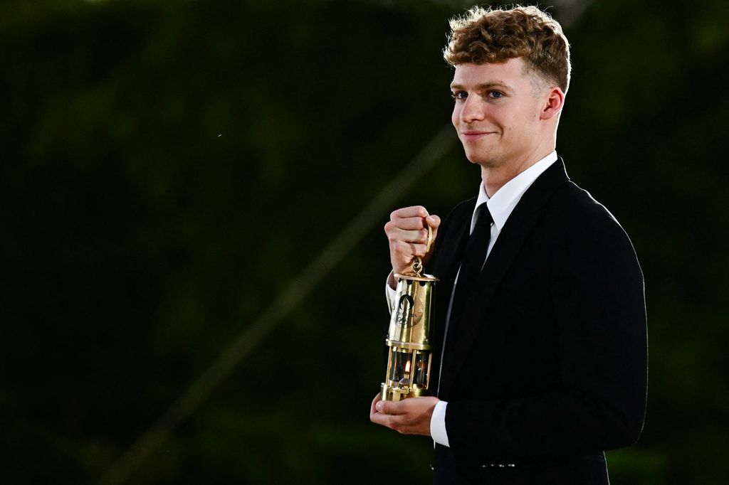 French swimmer Leon Marchand holds the Olympic flame during the closing ceremony of the Paris 2024 Olympic Games at the Jardin des Tuileries (Tuileries Garden), on August 11, 2024.