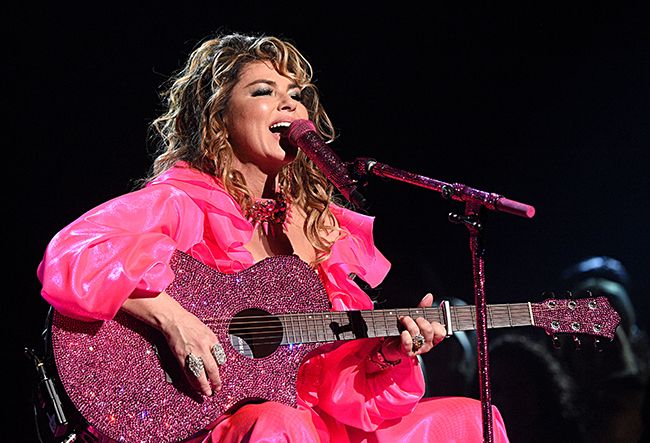 shania twain performing on stage with a guitar
