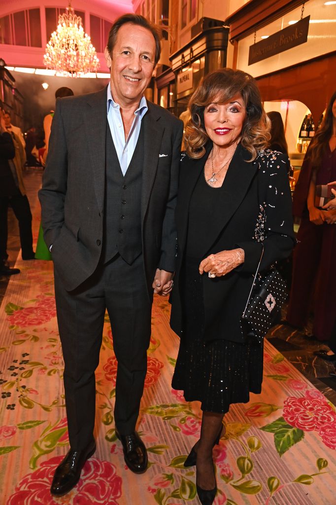 Percy Gibson and Dame Joan Collins pose in boutique in black outfits