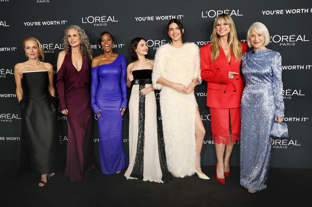 Gillian Anderson, Andie MacDowell, Aja Naomi King, Ariana Greenblatt, Kendall Jenner, Heidi Klum, and Helen Mirren pose on the red carpet, laughing and holding hands
