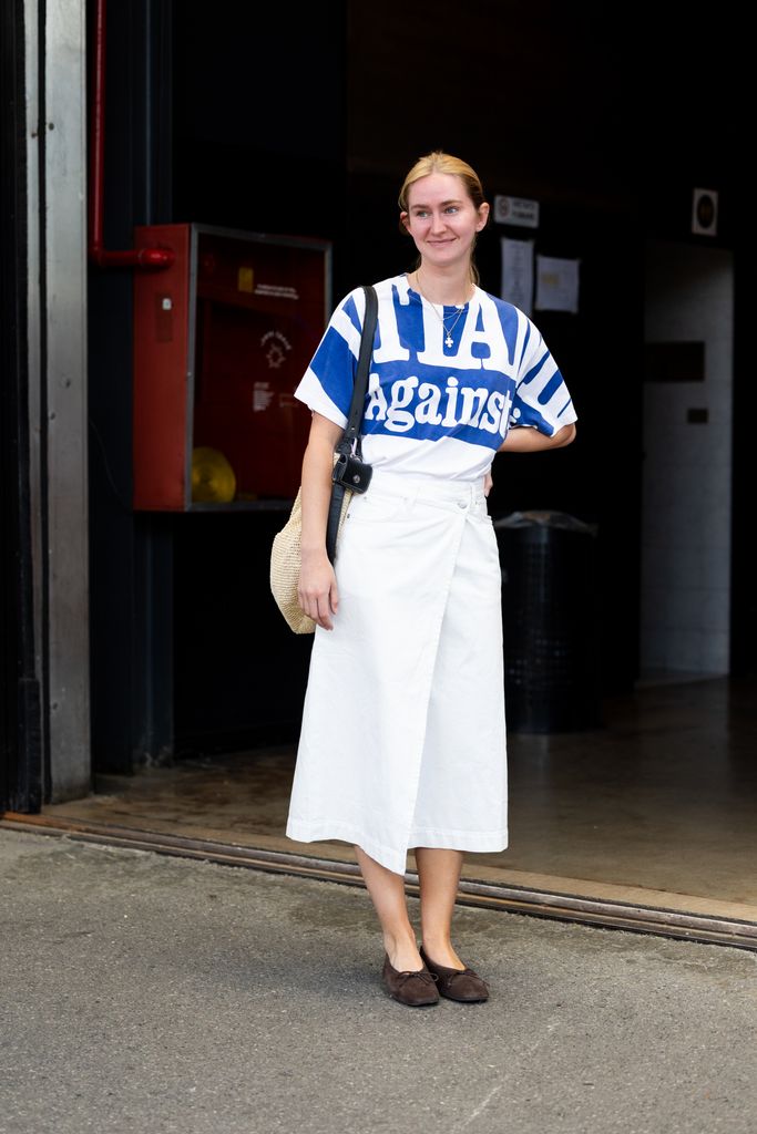  guest wears a blue and white printed t-shirt, a white maxi skirt, brown suede ballerinas and a black and beige cross-body bag at East Market vintage fair o