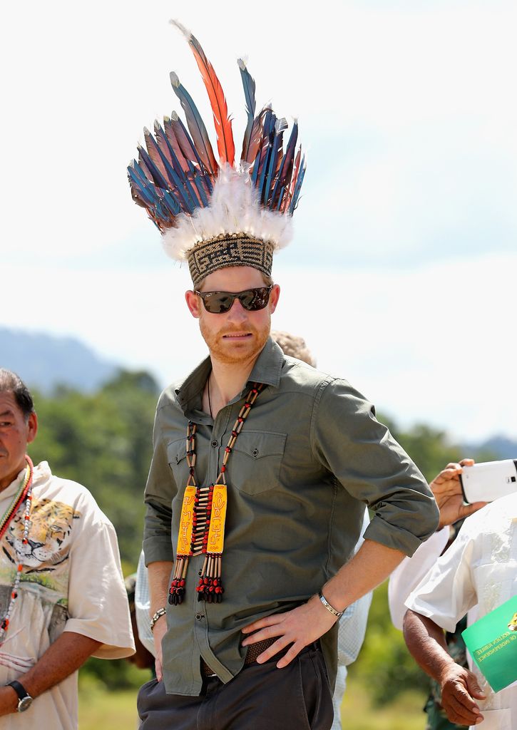 Prince Harry with a feathered headdress and green shirt