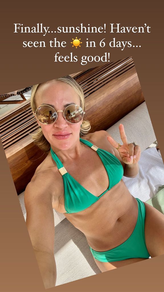 Carrie lying on a sun lounger in a green bikini posing for a selfie