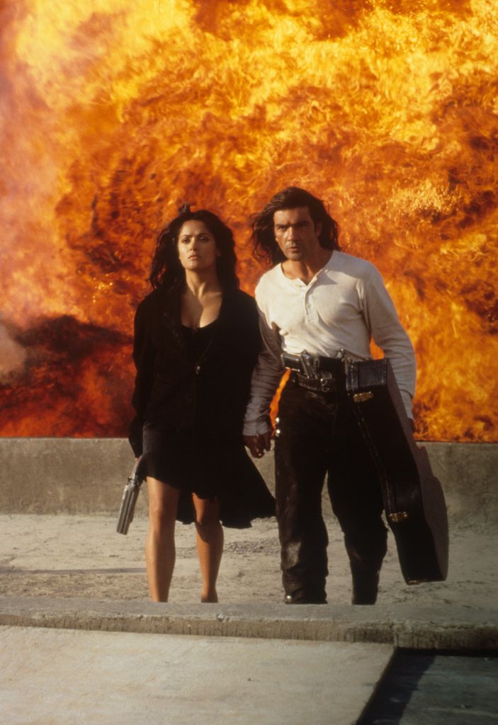 Antonio Banderas and Salma Hayek walking away from burning flames in a scene from the film 'Desperado', 1995.