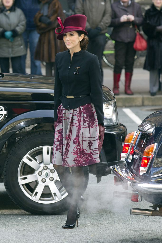 Mary between cars in berry hat 