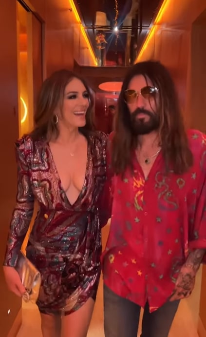 Elizabeth in a sparkly wrap dress beside billy ray cyrus