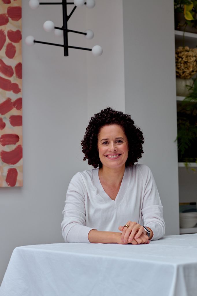 headshot of a smiling woman in a white top with curly hair 