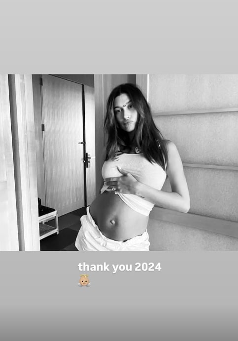 Hailey Bieber standing with her hand on her bump in black and white photo