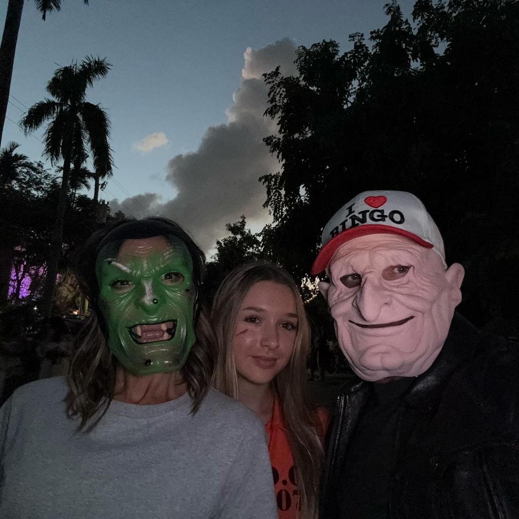 David and Victoria in Halloween masks with Harper in orange jumpsuit