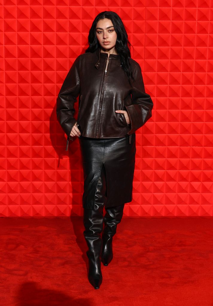 Charli XCX in black leather jacket, skirt and boots