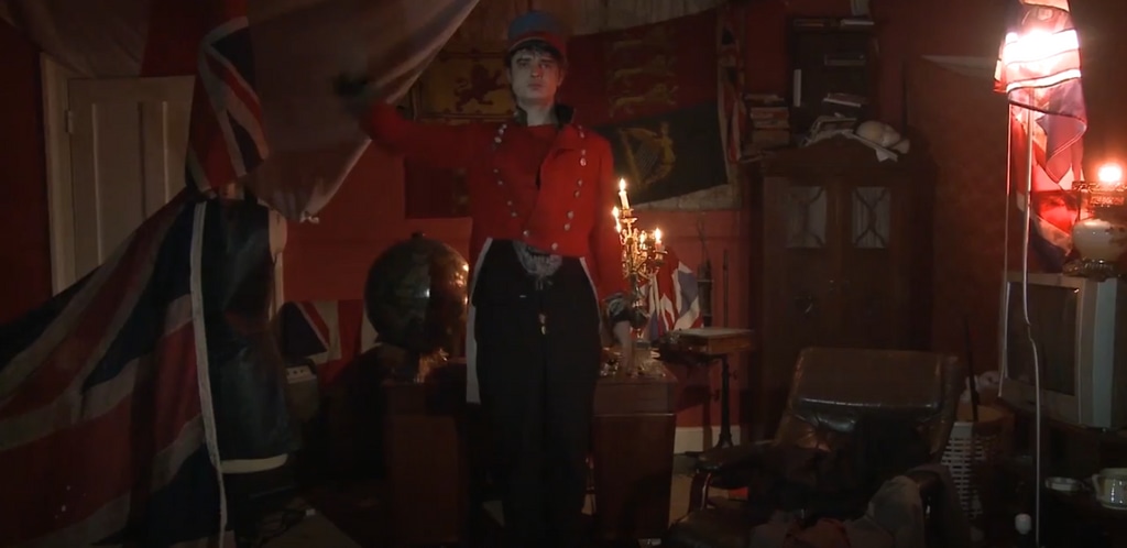 Pete Doherty in a red military jacket at home 