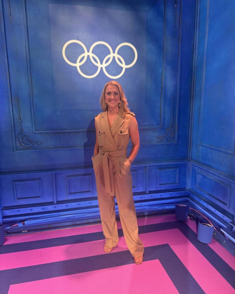 Laura Kenny in a jumpsuit in front of the Olympics logo