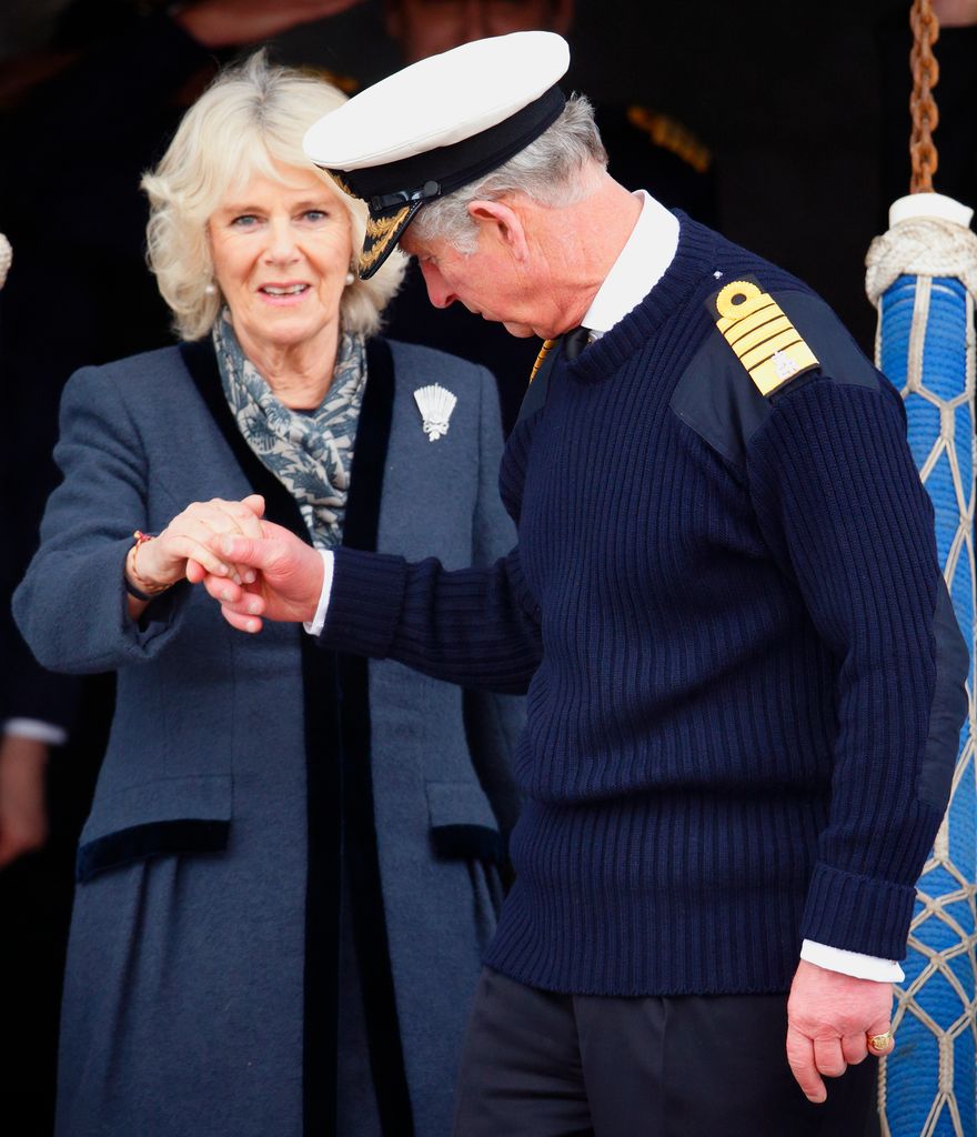 Charles holds Camilla's hand as they disembark HMS Illustrious in 2014 