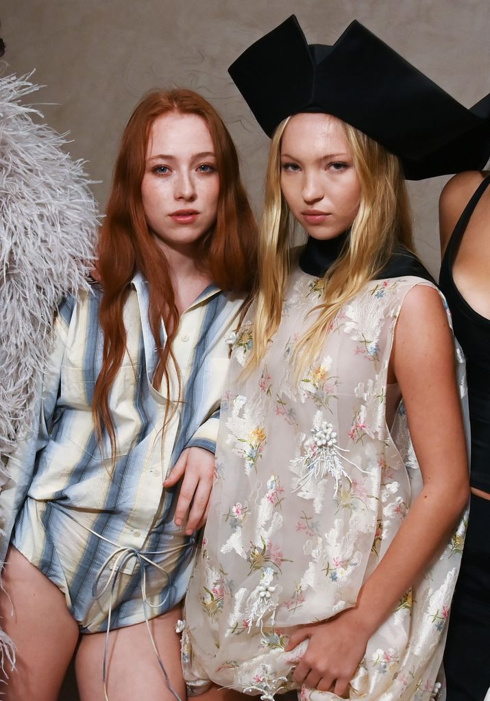 Stevie Sims and Lila Moss, Steveie wears a blue and white striped bodysuit and wears her long red hair in loose tousled waves