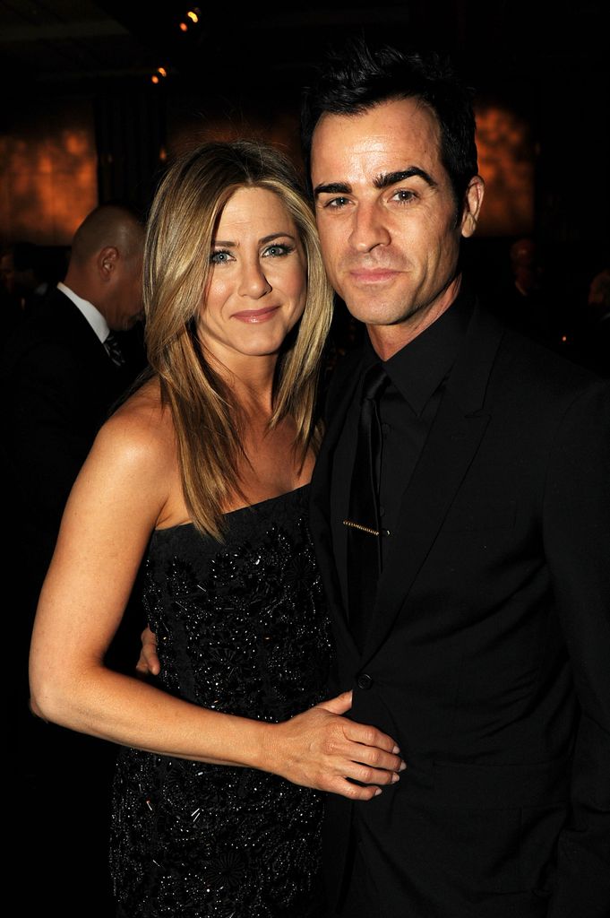 Jennifer Aniston in a black sparkly dress with arms around Justin Theroux in a black suit