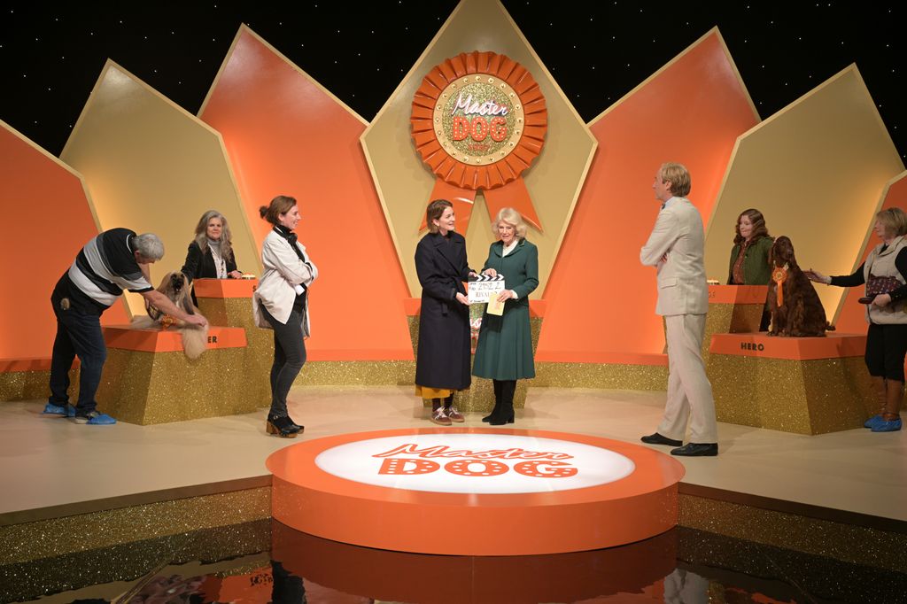 Queen Camilla holds a clapper board during a visit to the film set of TV Show 'Rivals'