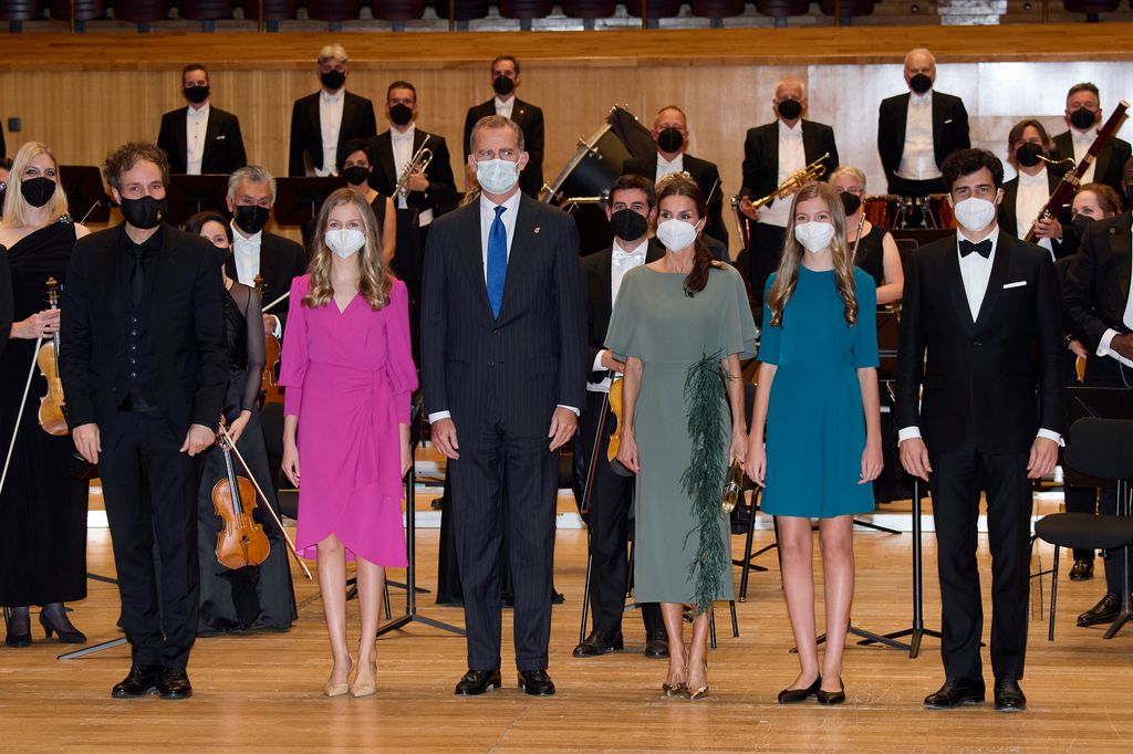 King Felipe VI of Spain, Queen Letizia of Spain, Crown Princess Leonor of Spain (L) and Princess Sofia of Spain stand on stage with musicians in face masks