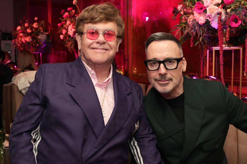 Elton John and David Furnish sitting on the couch at the Oscars party