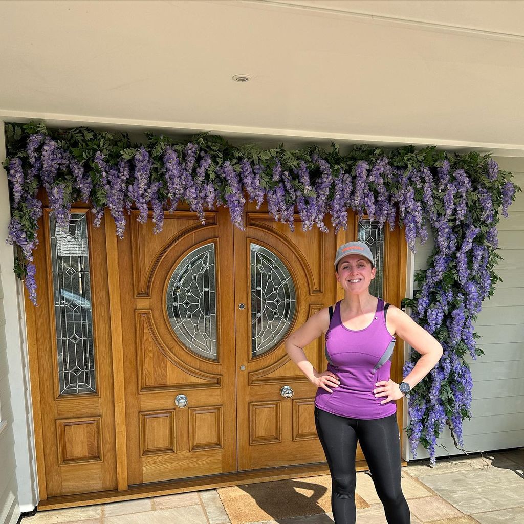 Natalie Cassidy standing in front of her door which is dress with wisteria