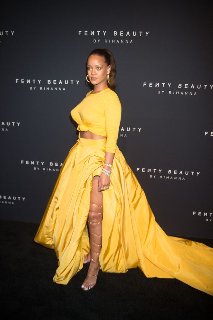 Rihanna poses in a yellow top and skirt 