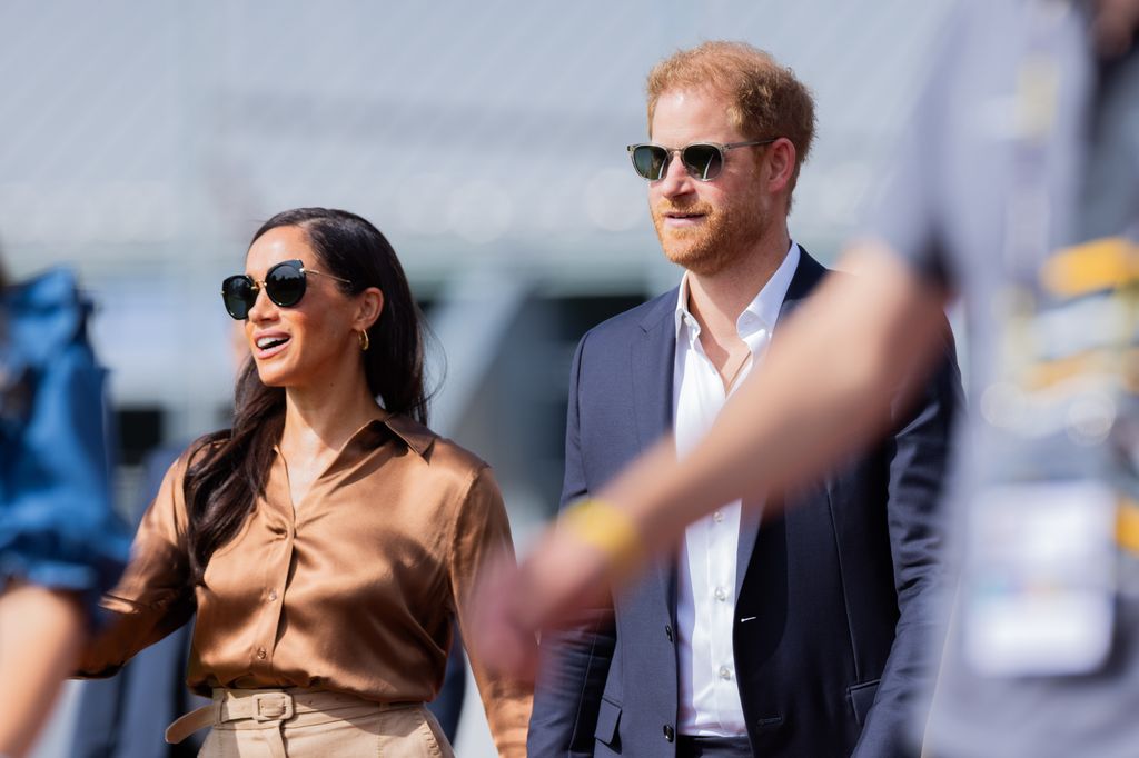 Prince Harry and Meghan Markle walking and holding hands whilst wearing sunglasses