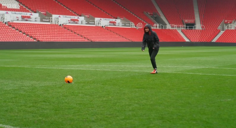 Woman standing in football field about to hit ball
