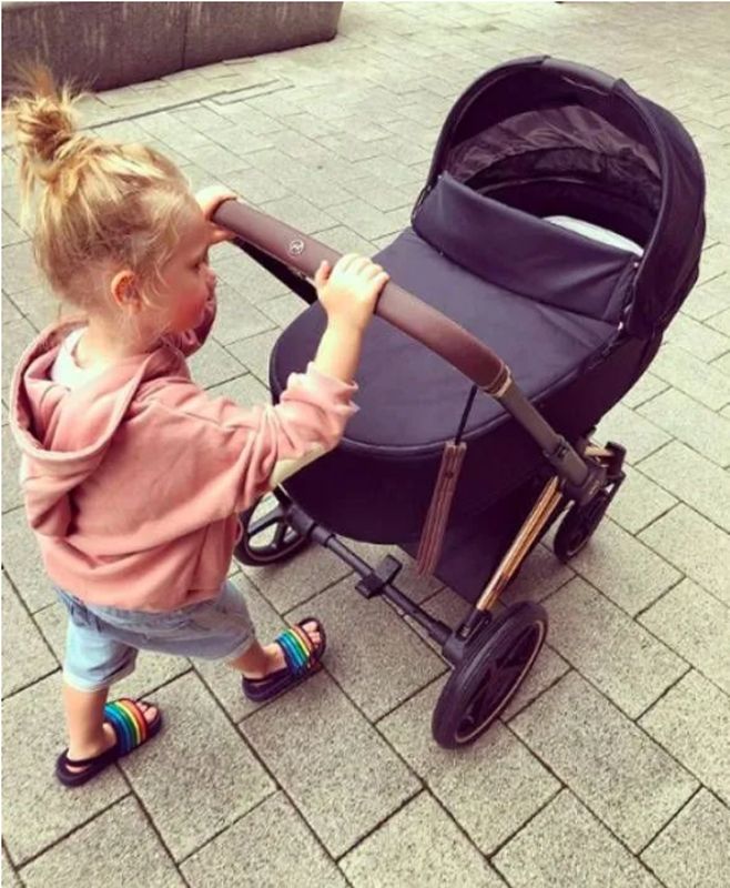 Charley Webb's son Bowie with his blonde hair in a messy bun pushing a pram