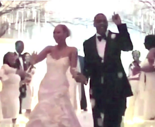 Beyonce in a wedding dress holding hands with jay-z in a suit, in a blurry photo of them walking down the aisle