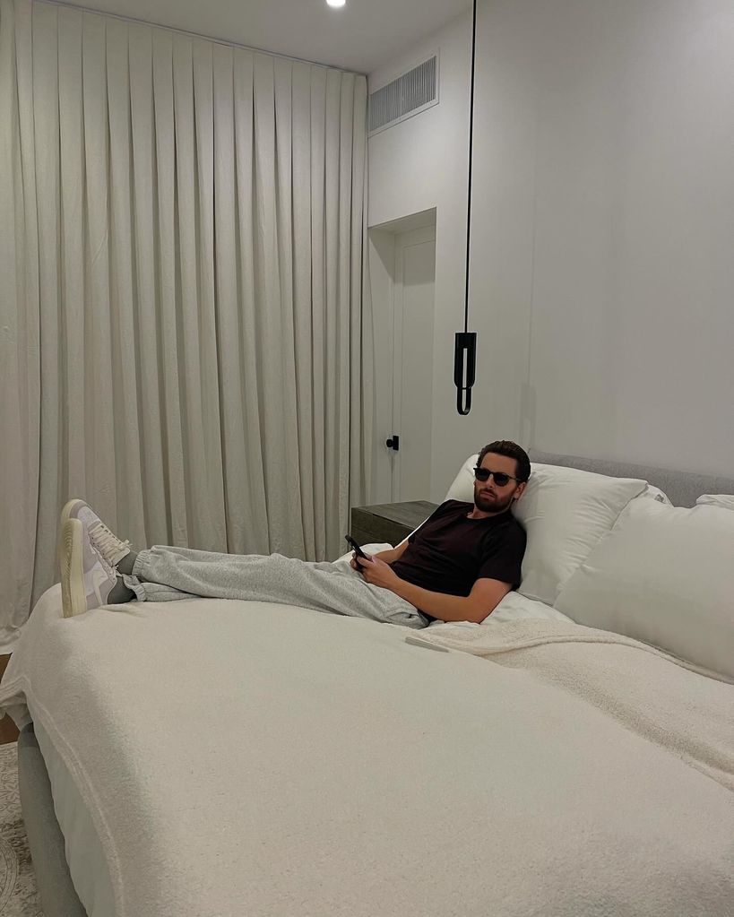 Scott Disick lying on a huge white bed