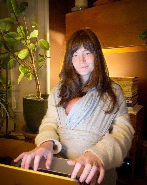 Natasha Raskin Sharp working with her baby in a sling