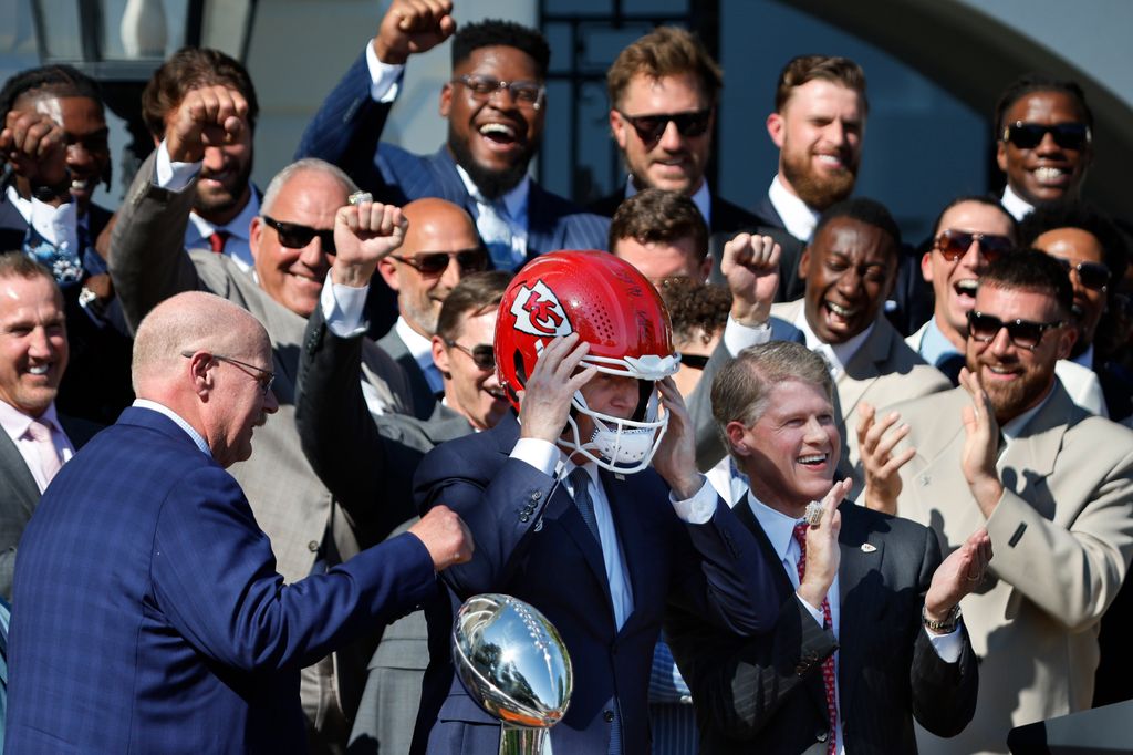 Harrison Butker (en haut, deuxième à droite) regarde le président américain Joe Biden mettre un casque qui lui a été offert par l'entraîneur-chef des champions du Super Bowl de la NFL, Andy Reid (à gauche), et le PDG Clark Hunt des Chiefs de Kansas City sur la pelouse sud du White. Maison le 31 mai 2024 à Washington, DC.  Les Chiefs ont battu les 49ers de San Francisco 25-22 en prolongation pour remporter le Super Bowl 2024.