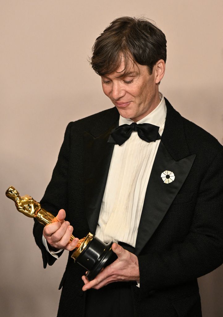 Irish actor Cillian Murphy looks at his Oscar while posing for photos in the press room