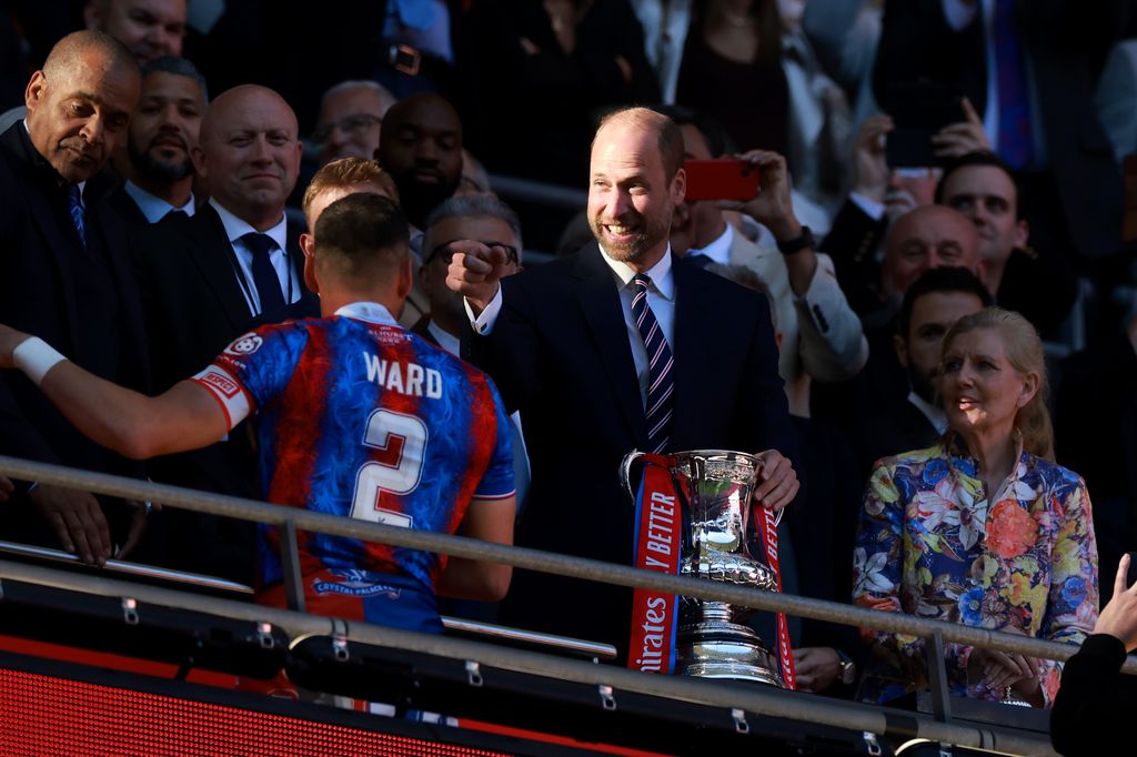 Prince William gestures towards Joel Ward of Crystal Palace, while he holds the FA Cup trophy