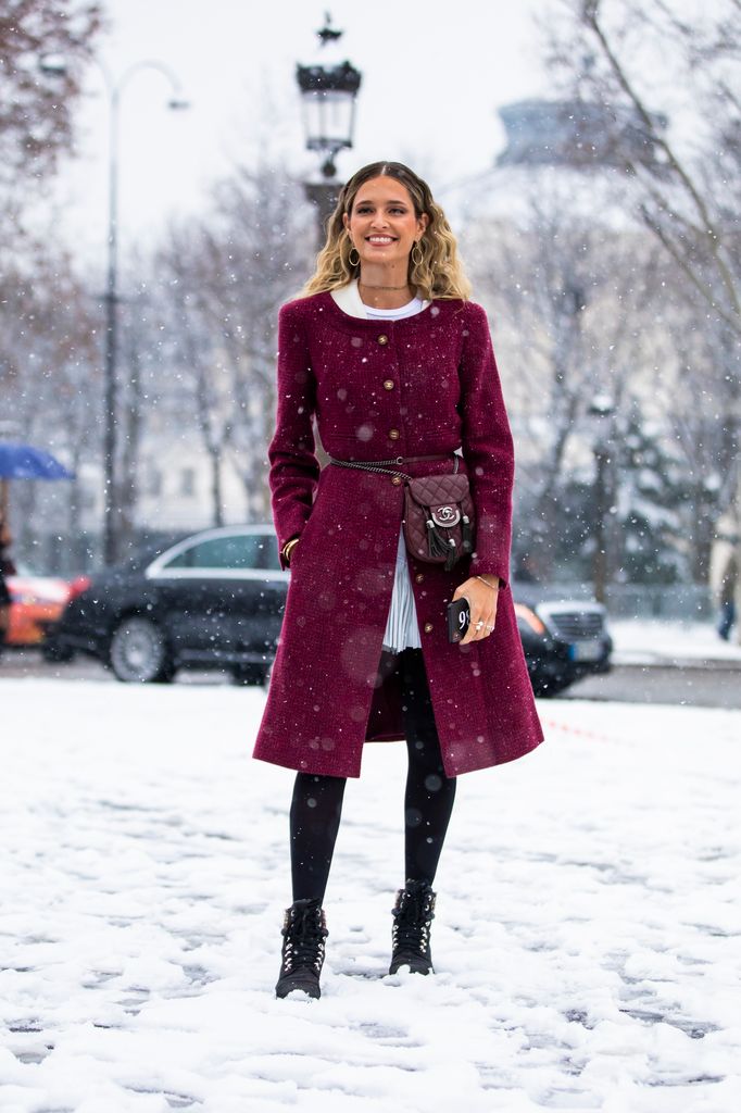 Helena Bordon, wearing a burgundy coat with gold buttons and a matching belt is all about timeless style. Paired with black tights and lace-up boots, it’s both feminine and warm. The chic accessories add a sophisticated touch, making it perfect for embracing snowy weather in elegant style.