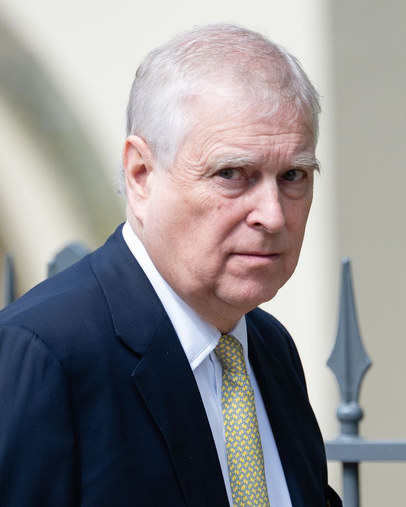 Andrew Mountbatten Windsor porte un costume bleu marine et une cravate jaune. 