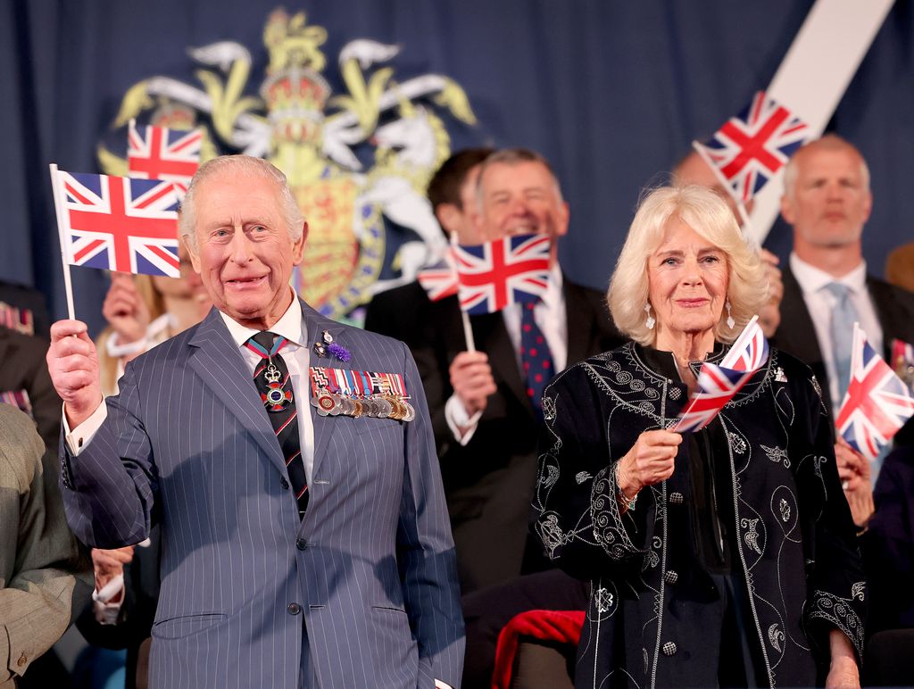 king charles and queen camilla waving flags at concert