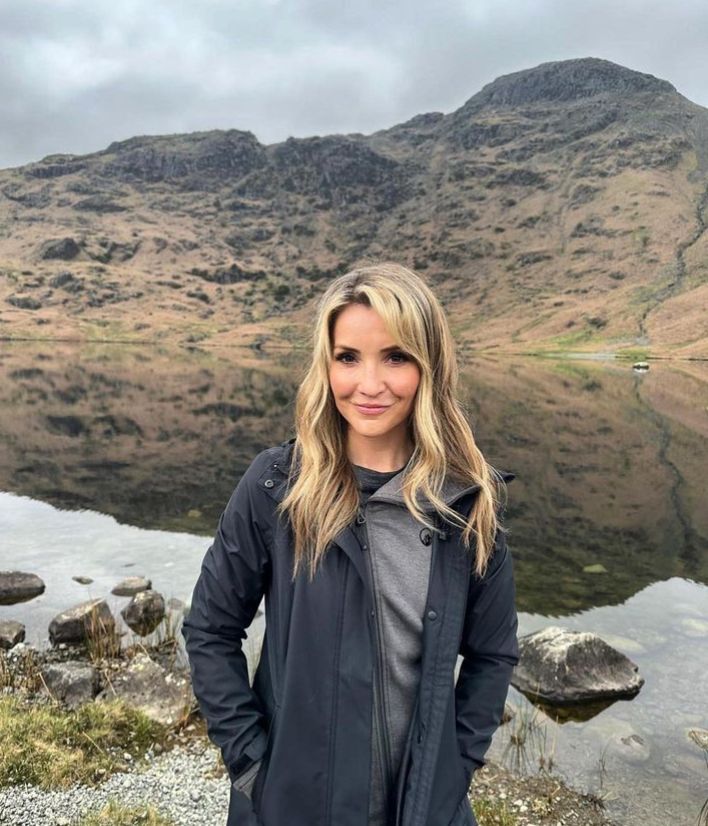 Helen Skelton in waterproof coat in front of lake and mountains