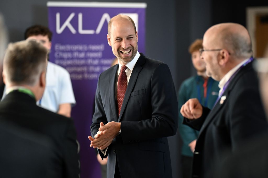 Prince William laughing talking to group of men
