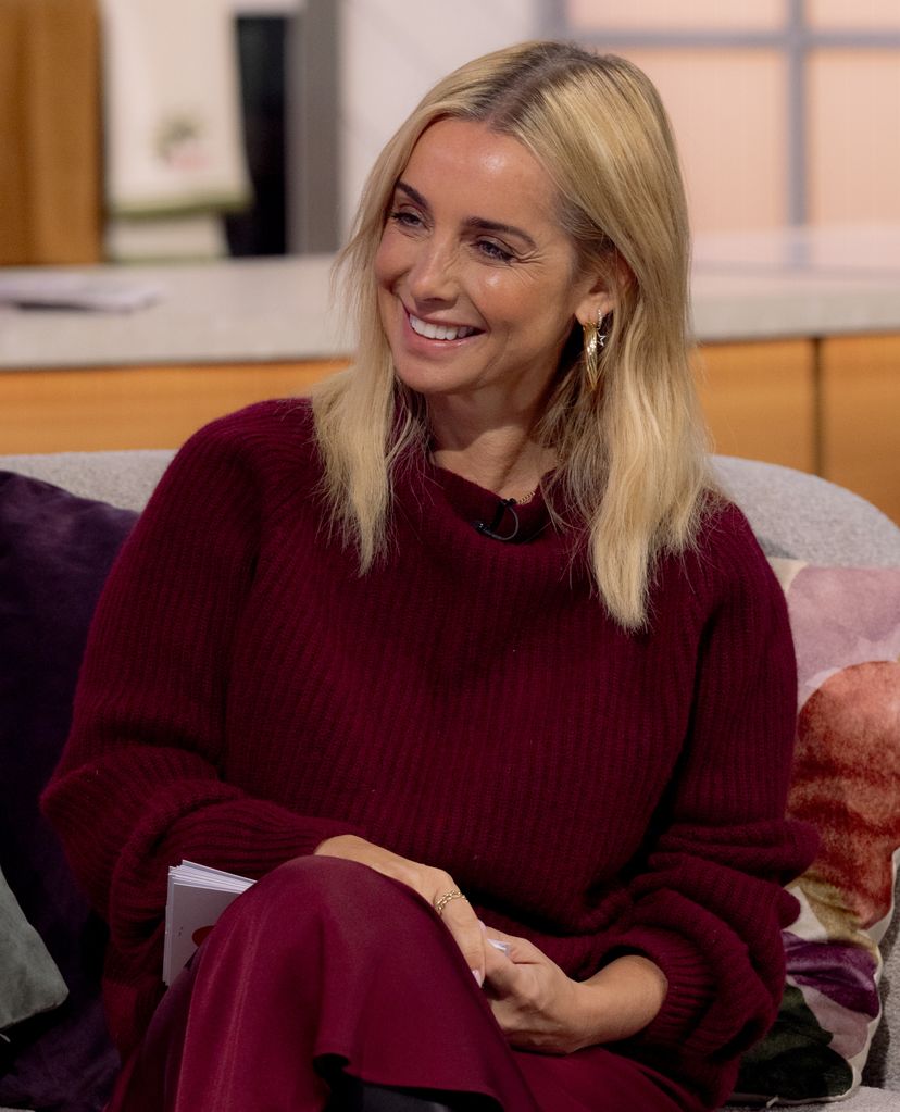 Louise Redknapp tersenyum dengan jumper merah