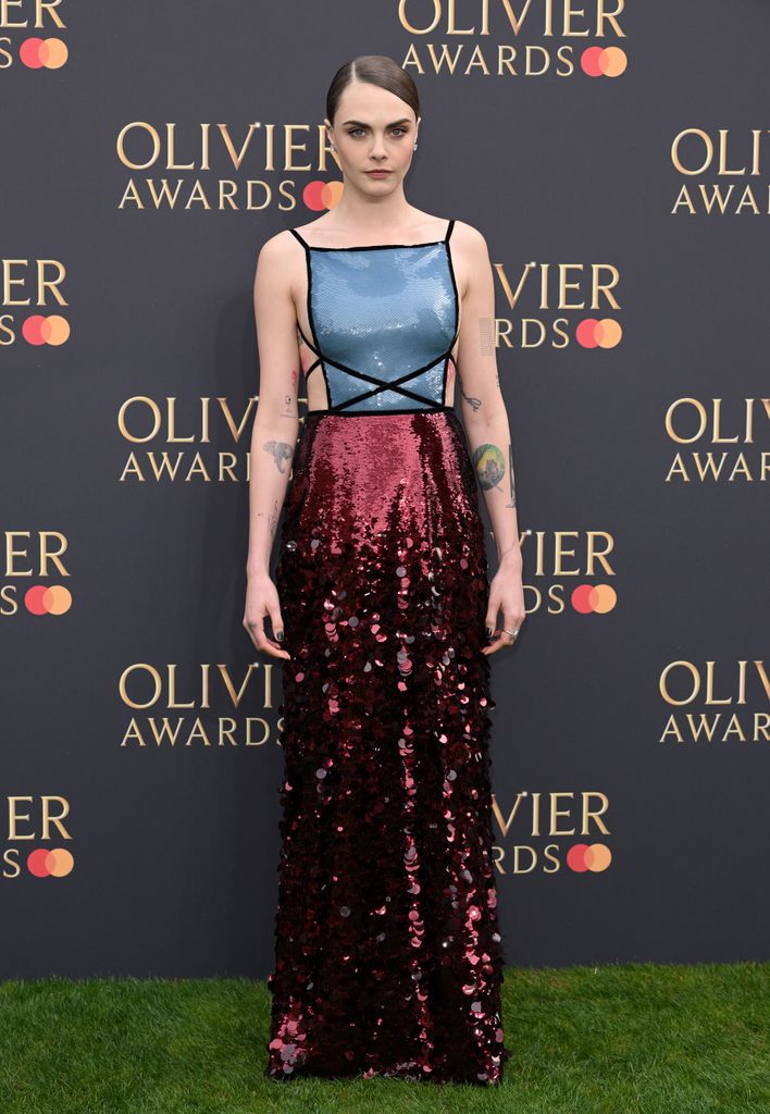 Cara Delevingne attends The Olivier Awards 2024 at The Royal Albert Hall on April 14, 2024 wearing a red and blue sequin gown