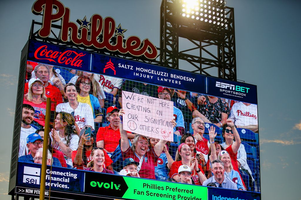 A fan holds up a sign during a kiss cam segment in the game between the Philadelphia Phillies and the Los Angeles Angels at Citizens Bank Park on July 18, 2025 in Philadelphia, Pennsylvania. The sign references the Astronomer CEO, Andy Byron, who was seen on a kiss cam during a Coldplay concert that led him to resign from the company
