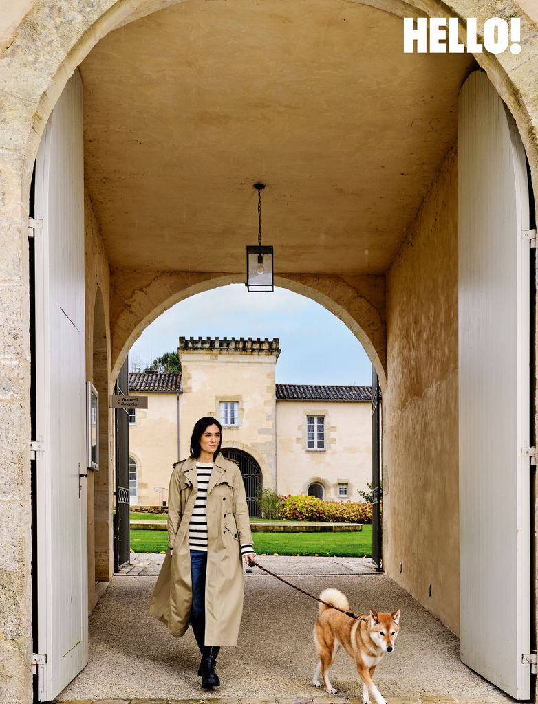 Amélie dans un manteau de biege avec son chien à l'entrée du château toulouse-lautrec