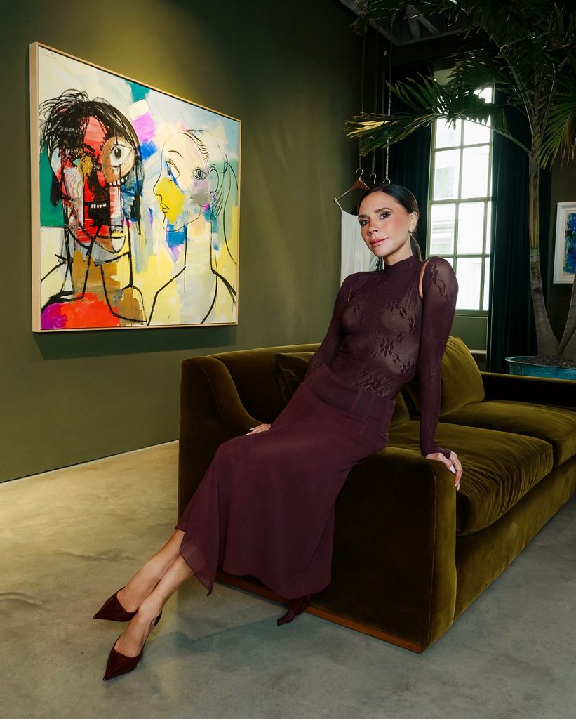 Victoria Beckham berpose di sofa dengan pakaian penuh burgundy