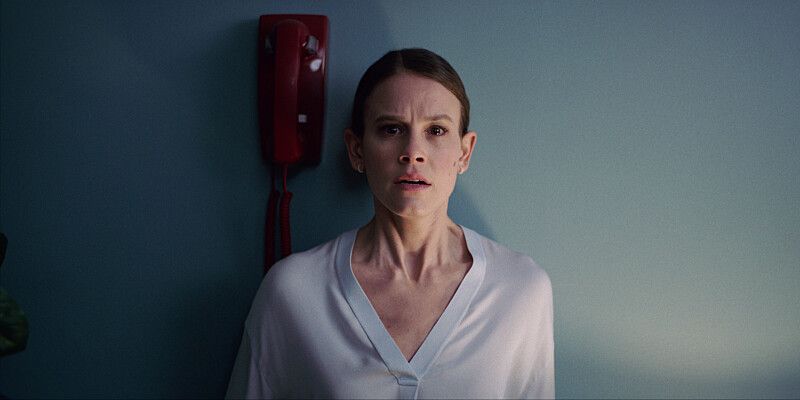 woman in white shirt standing against wall