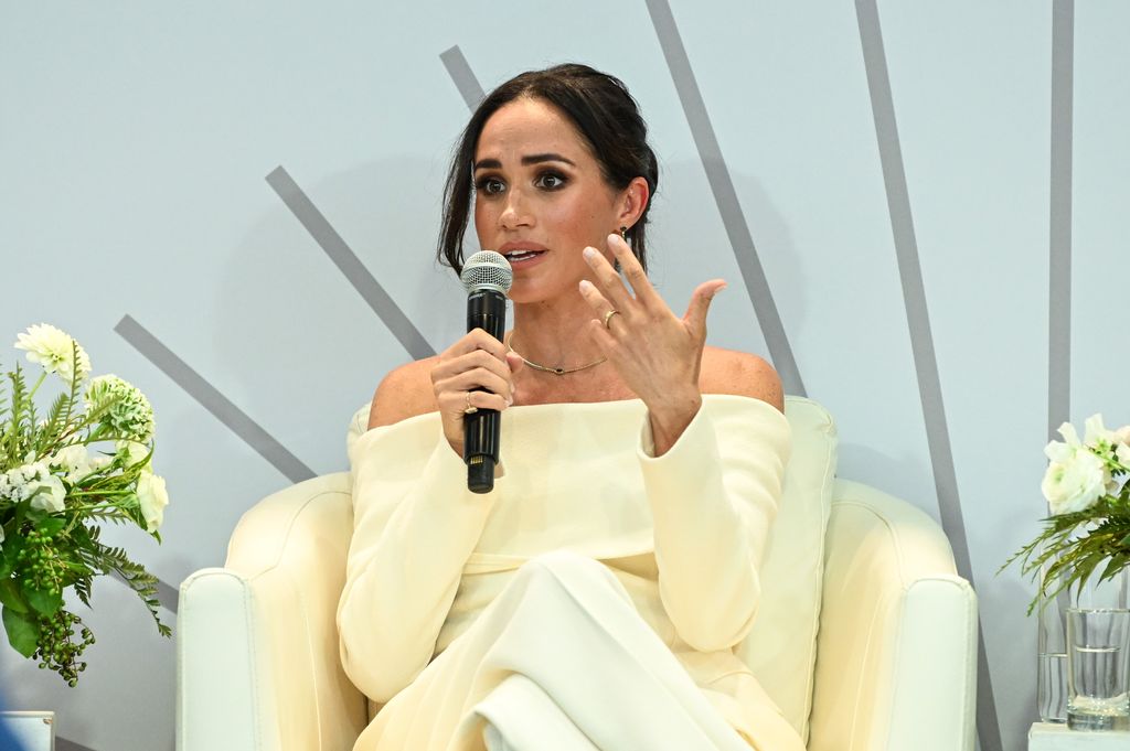 Meghan Markle in a cream suit with a microphone