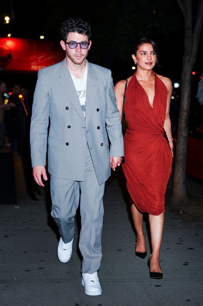 Nick Jonas and Priyanka Chopra in red dress walking at night